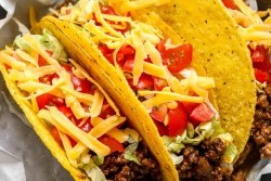 Tacos topped with cheese and tomatoes